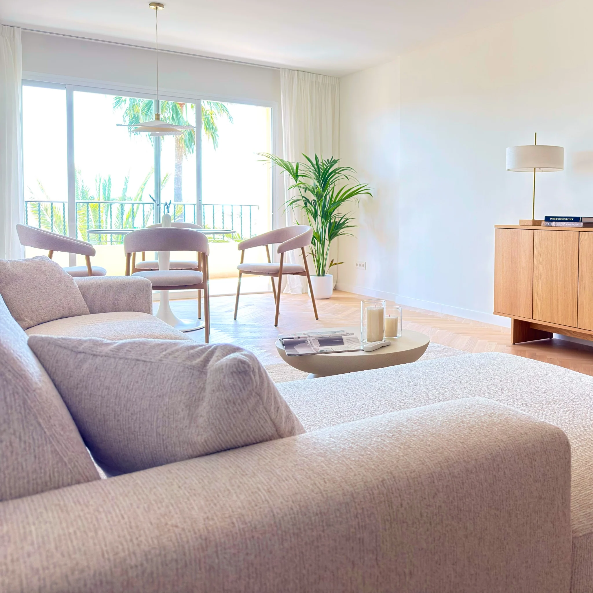 Bright living and dining room opening onto a palm-lined terrace